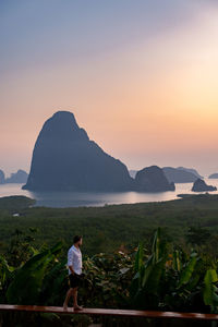 Man standing on mountain against sky during sunset