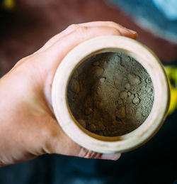 Close-up of hand holding powder in container