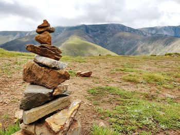Stack of rocks on field against sky