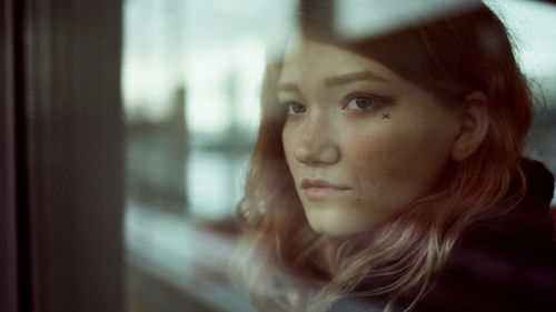 Beautiful woman stands in a parking lot and looks through a window