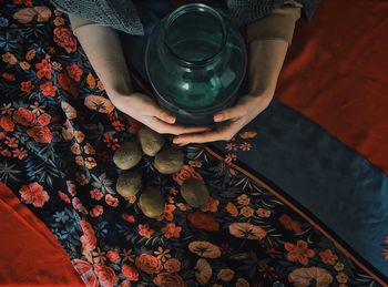 Cropped hand of woman holding container with kiwi on floor