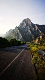 Road leading towards mountains against sky