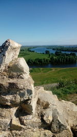 Scenic view of rocks by sea against clear blue sky