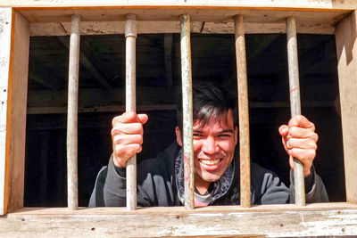 Portrait of smiling man holding umbrella against building