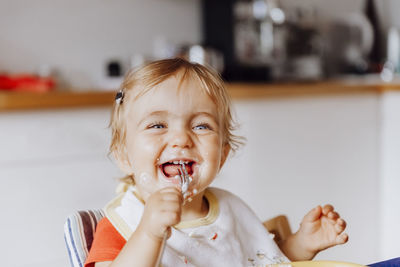 Smiling cute girl eating food at home