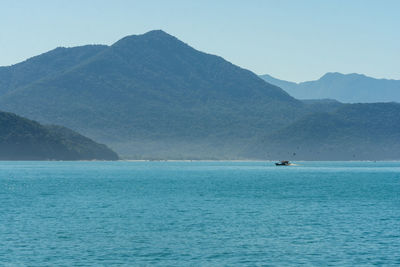 Scenic view of sea and mountains against clear sky