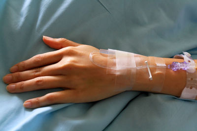 Close up patient's hands giving the saline solution on bed 