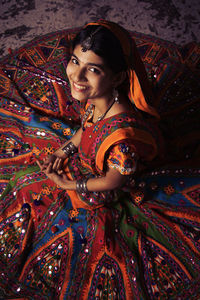 Portrait of young woman standing against curtain