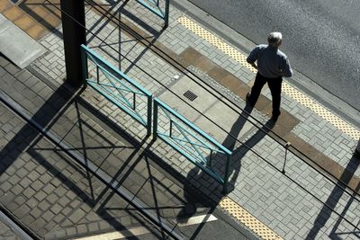 High angle view of man standing on sidewalk during sunny day
