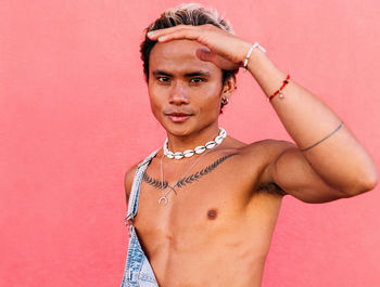 Man shielding eyes against pink wall