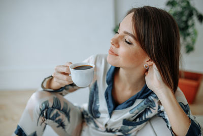 Young woman having coffee at home