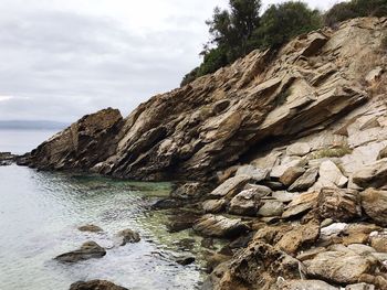 Rock formations by sea against sky