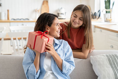 Side view of young woman using phone at home