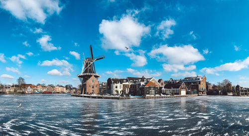 Traditional windmill by building against sky