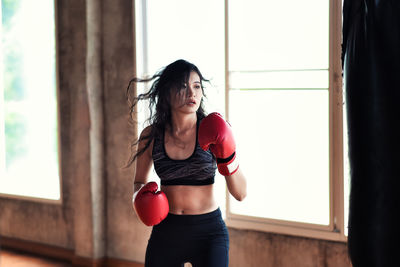 Young woman hitting punching bag in studio