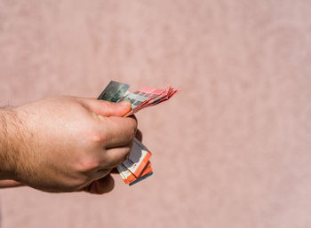 Close-up of hand holding eyeglasses against wall
