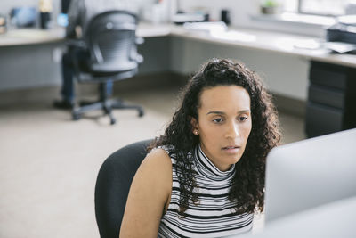 Businesswoman using computer while male colleague in background