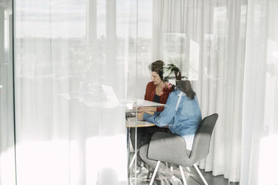 Female colleagues working in office seen through glass