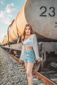 Portrait of smiling young woman standing on railroad track