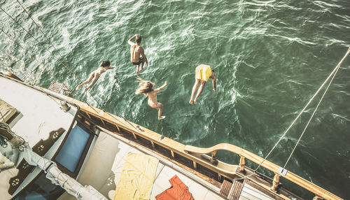 High angle view of friends diving from boat into sea