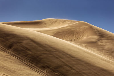 Low angle view of sand dunes against clear sky