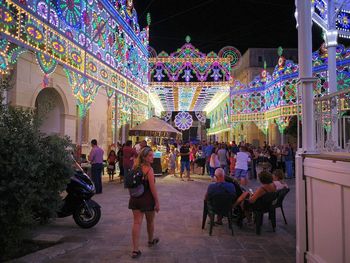 Group of people at illuminated building in city
