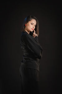 Young woman standing against black background