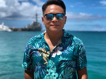 Portrait of man wearing sunglasses standing against sea