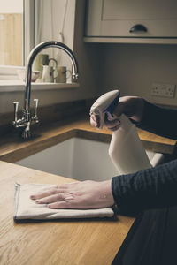 Cropped hands of woman cleaning kitchen counter at home