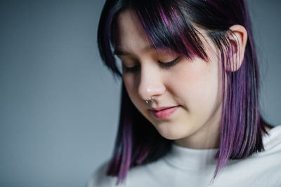Portrait of a beautiful young girl with purple hair close-up on a gray background