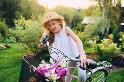 Smiling girl riding bicycle against trees