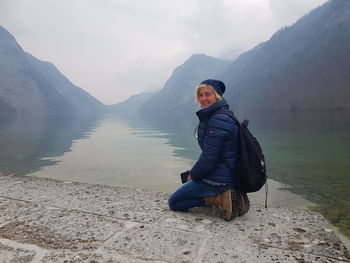 Man sitting in lake against mountains during winter