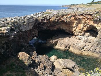 Rock formations by sea against clear sky