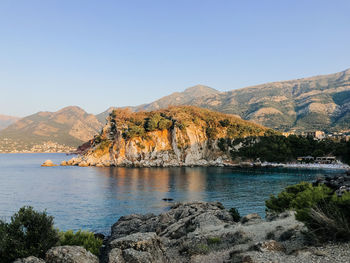 Scenic view of sea and mountains against clear sky