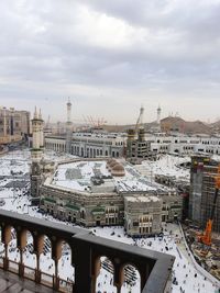 High angle view of city buildings against cloudy sky