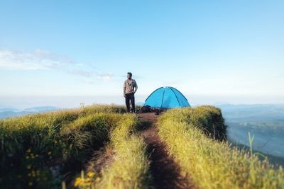 Rear view of man in tent on land against sky