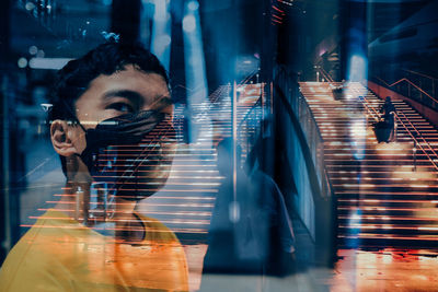 An in camera double exposure shot of a boy wearing a face mask in a mall at night