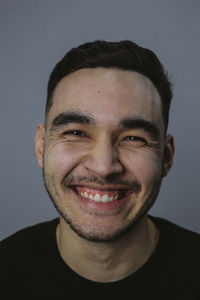 Close-up portrait of happy young man against wall