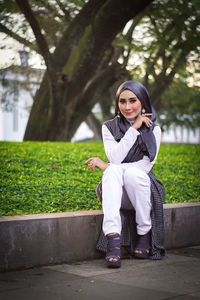 Portrait of woman in hijab sitting at park during sunset