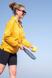 Side view of young woman exercising against clear sky