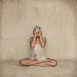 Young woman sitting against wall