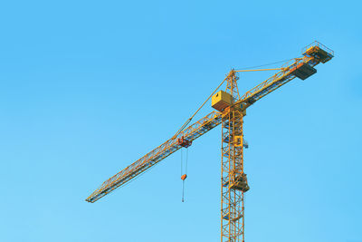 Low angle view of crane against clear blue sky