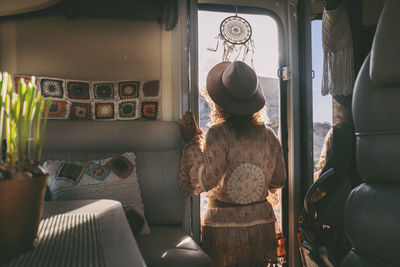 Rear view of woman looking through motor home