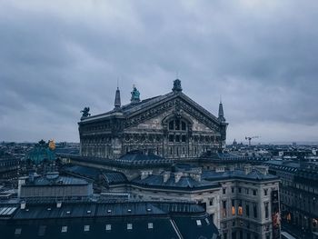 Buildings in city against cloudy sky