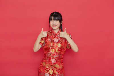 Portrait of a smiling young woman against red background