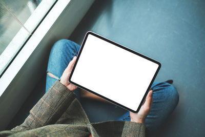 Midsection of woman using digital tablet while sitting in car