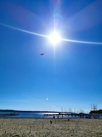 Airplane flying over sea against clear blue sky on sunny day