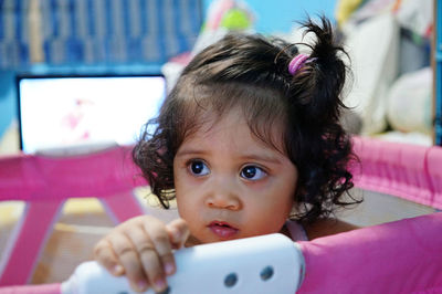 Close-up of baby girl sitting in crib at home