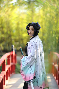 Young woman standing against trees