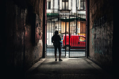 Rear view of man standing near metal gate